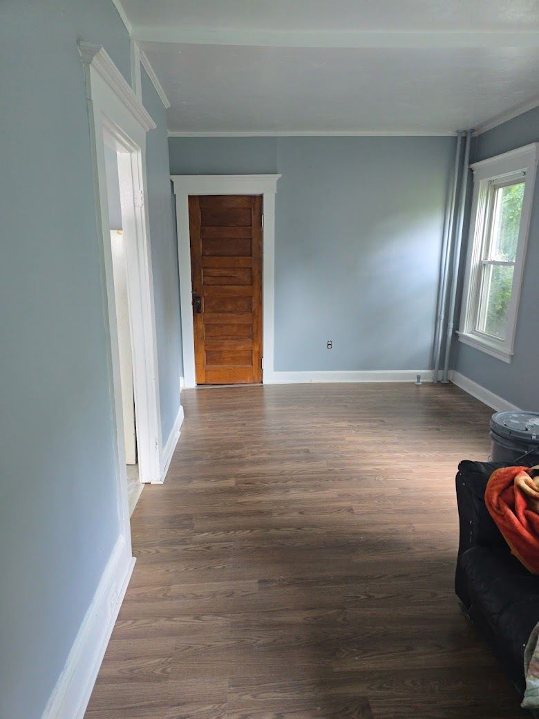 Living room after refresh with matching blue-gray paint, restored wood door and continuous plank flooring.