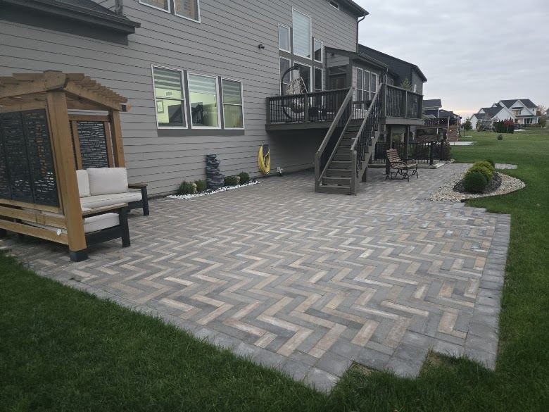 Finished herringbone paver patio with cedar pergola, seating area and landscaped border.
